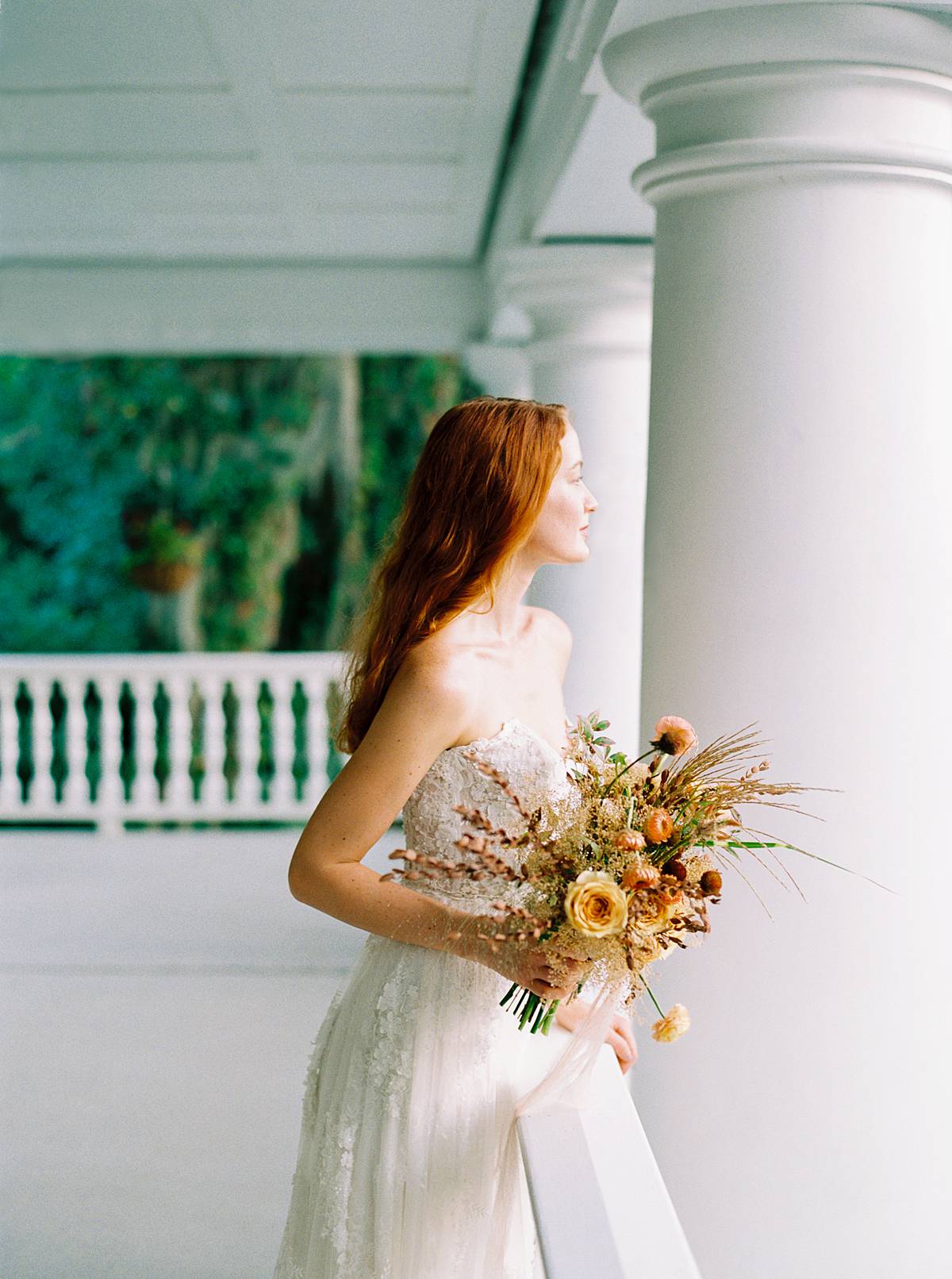 charleston bride on her wedding day on veranda overlooking magnolia plantation and gardens with bouquet